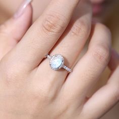 a close up of a person's hand with a ring on their finger and an oval shaped diamond in the middle