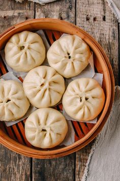 a bowl filled with dumplings on top of a wooden table next to napkins