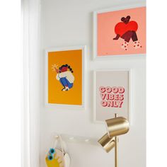 three framed pictures hang on the wall above a lamp and other art pieces in a white room