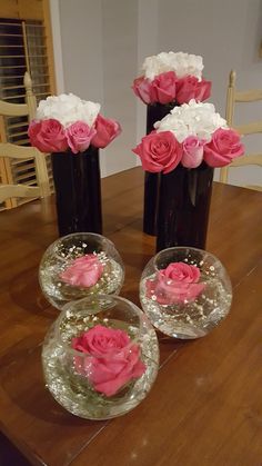 three vases filled with pink and white flowers on top of a wooden table next to each other