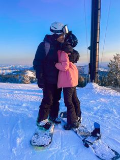 two people standing on top of a snow covered slope