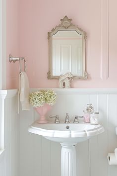 a white pedestal sink sitting under a mirror next to a wall mounted faucet