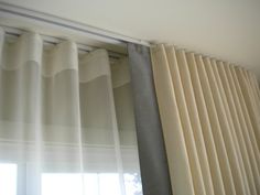 curtains hanging on the side of a window in front of a white curtain with grey trim