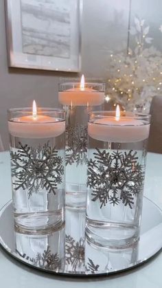 three candles are sitting on a plate with snowflakes in them and lit up