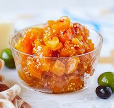 there is a small glass bowl filled with jelly and olives next to other candies