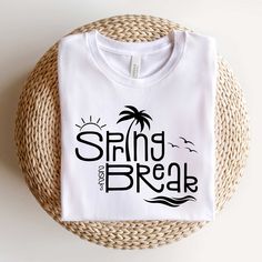 a white t - shirt with the words spring break on it sitting next to a woven basket