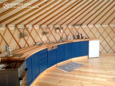 the interior of a yurt with blue cabinets and wood flooring is very large