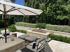 an outdoor dining area with chairs, umbrellas and water feature in the back yard