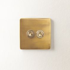 a gold light switch on a white wall with two knobs in the same position