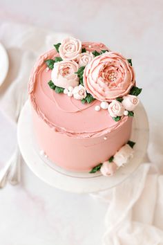 there is a pink cake with flowers on the top and bottom, sitting on a white plate