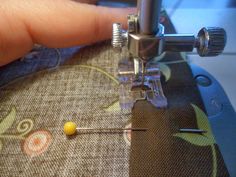 someone is stitching the thread on their sewing machine with a needle and yellow pin