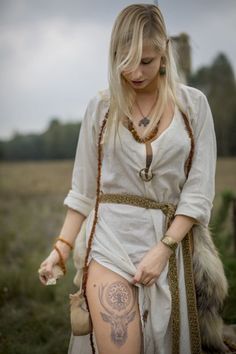 a woman in a white dress with tattoos on her body and holding a small teddy bear