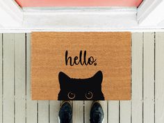 a door mat with a black cat's head on it and the words hello