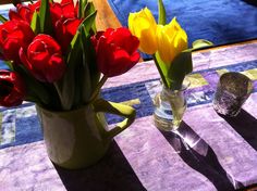 two vases filled with red and yellow tulips on top of a table