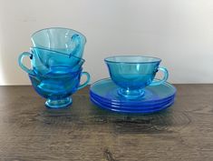 two blue glass cups and saucers on a wooden table