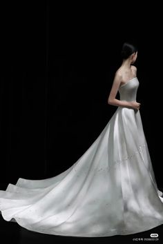 a woman in a white wedding dress standing on a black background with her back to the camera