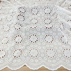 a white doily with small holes on the top and bottom, sitting on a wooden surface