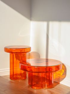 two orange glass tables sitting on top of a wooden floor