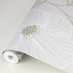 a white flower wallpaper with gold foiling on the edges and bottom, next to a roll of toilet paper