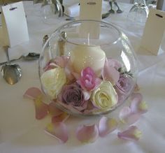 there is a glass bowl with flowers in it and tags on the table next to it