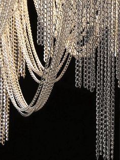 a chandelier with chains hanging from it's sides in front of a black background