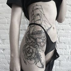 a woman's stomach with flowers and a ship tattoo on her side ribcage