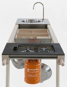 an orange propane burner is attached to the side of a table with a sink