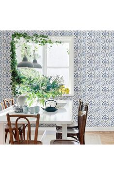 a dining room table with four chairs and a potted plant on the window sill