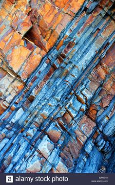 an orange and blue rock wall with cracks in it