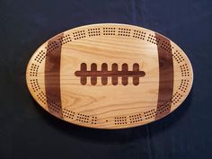 a football shaped wooden cutting board with holes in the middle on a black tablecloth