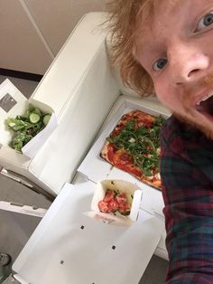 a man is taking a selfie with his pizza in front of him on the plane