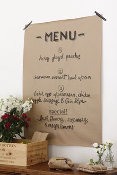 a menu hanging on the wall next to some flowers and other things in front of it