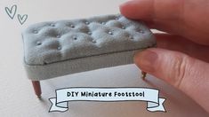 someone is holding a miniature footstool made out of fabric and wood legs, with the word diy miniature footstool on it