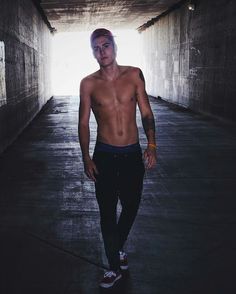 a shirtless man is walking through a tunnel with his hands in his pockets and no shirt on