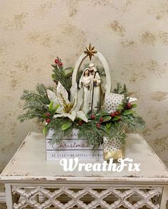 a white table topped with christmas decorations and a nativity figurine sitting on top of it