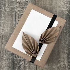 a gift wrapped in brown paper with a black ribbon