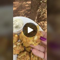 a person is holding up some food on a plate with dip in the middle and another hand reaching for it