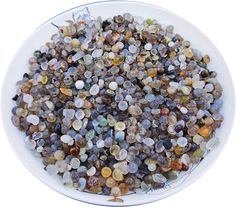 a white bowl filled with lots of different colored rocks on top of a white table