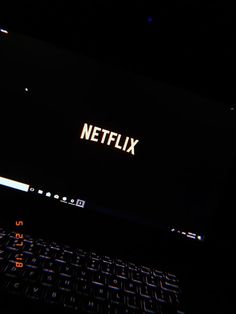 a laptop computer with the word netflix lit up on it's screen in the dark