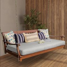 a wooden swing bed with pillows on it in front of a wood paneled wall