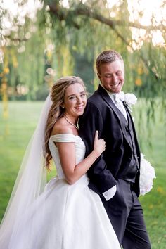 a bride and groom pose for a photo in front of a tree at their wedding