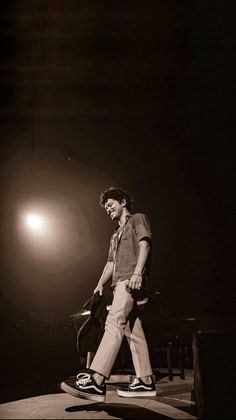 a man standing on top of a stage next to a black and white photo in the dark