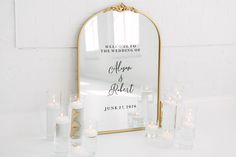 a mirror and candles on a table in front of a white brick wall with the words welcome to the wedding