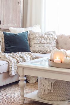 a living room filled with furniture and pillows on top of a table next to a window