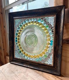 a decorative glass plate sitting on top of a wooden table next to a window in a room