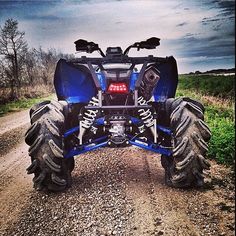 a blue four - wheeler parked on the side of a dirt road