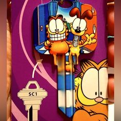 a cartoon key chain with garfield and cat characters attached to it, in front of a purple background