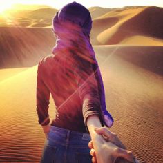 two people holding hands in the desert at sunset