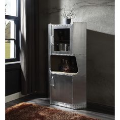 a tall metal cabinet sitting in front of a window next to a rug and wall