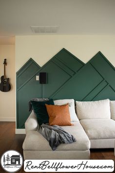 a white couch sitting in front of a green headboard on top of a wall